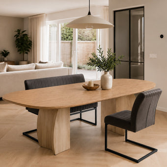 eettafel deens ovaal dualis in een woonkamer  met bank en stoel eraan geschoven.