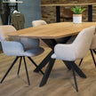 eettafel deens ovaal linea in onze showroom geplaatst met 4 witte stoelen en een blad met de kleur naturel.