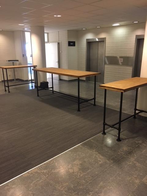 Hoge bartafel met een zwart steigerbuis onderstel en een vurenhouten tafelblad waar personeel pauze kan gaan houden.