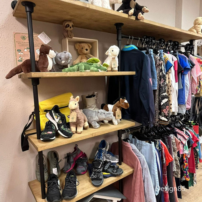 Industrieel kledingrek muur met legplanken en hanggedeelte gevuld met kinderkleding