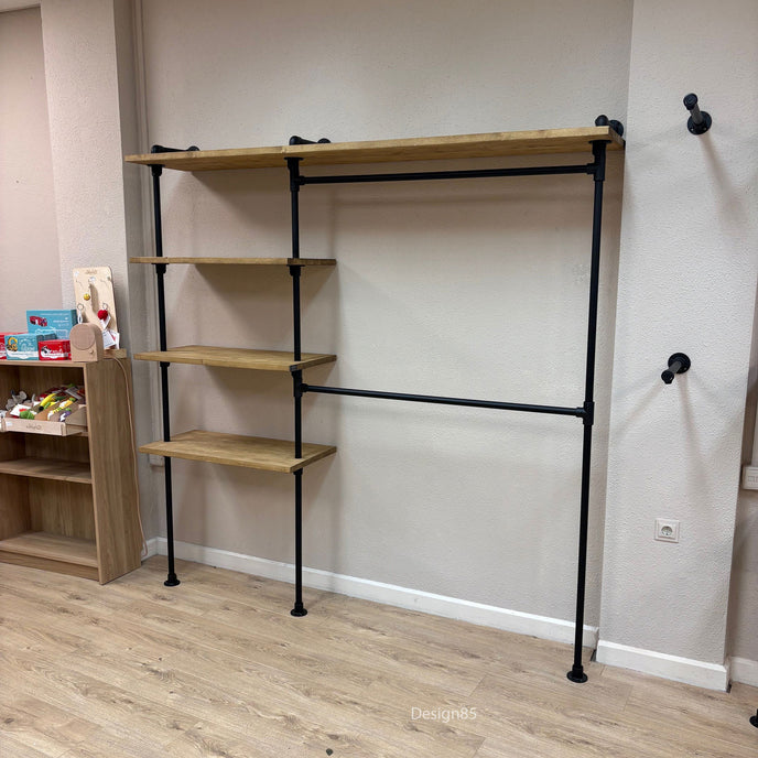 Industrieel kledingrek voor kinderen aan de muur met houten legplanken en zwart stalen frame in een lichte ruimte.