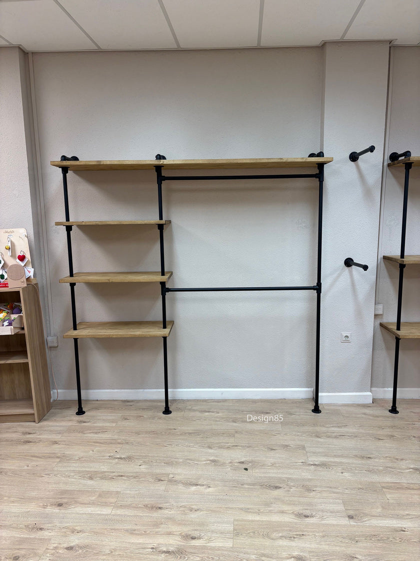 Kinder kledingrek aan de muur met open vakken, zwarte buizen en houten planken voor kleding en opbergruimte.