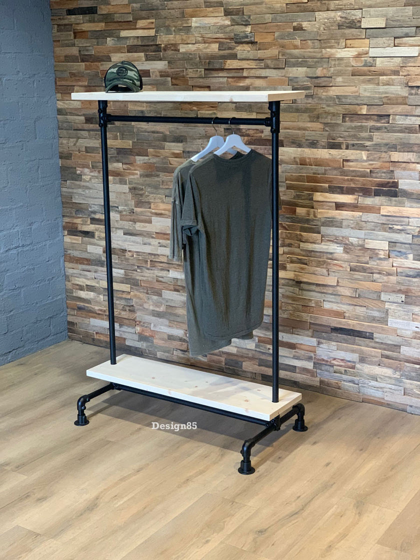 Kledingrek wielen planken in industriële stijl met witte houten legplanken, zwarte buizen en hangende kleding.