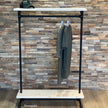 Industrieel kledingrek wielen planken van zwarte steigerbuizen met twee witte houten planken en kledingroede.