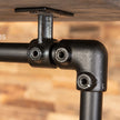 Close-up van de zwarte metalen buiskoppeling onder de houten plank van het kledingrek