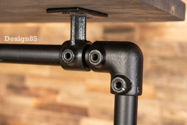 Close-up van de zwarte metalen buiskoppeling onder de houten plank van het kledingrek
