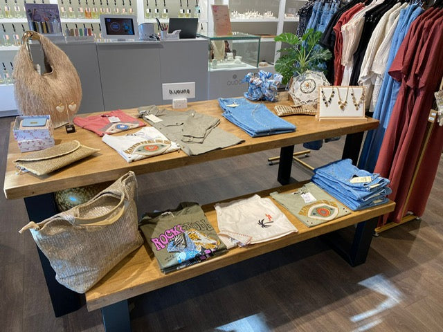 Presentatietafel winkel van hout en zwart staal met kleding en accessoires in een kledingzaak.