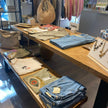 Grote presentatietafel winkel van Design85 met kleding, sieraden en tassen op twee houten niveaus.