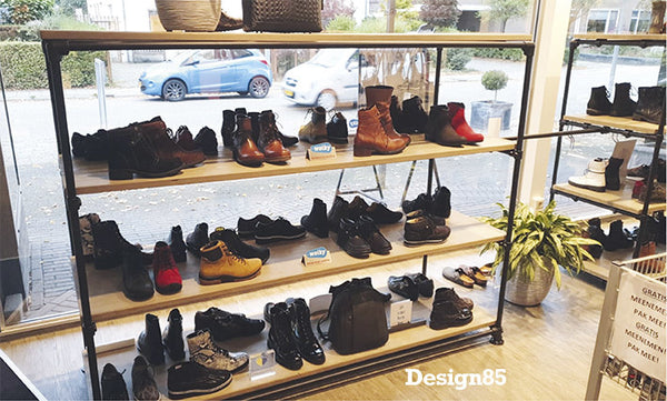 Steigerbuis kast met zwarte steigerbuizen die wordt gebruikt in een schoenenwinkel met diverse schappen voor schoenen.