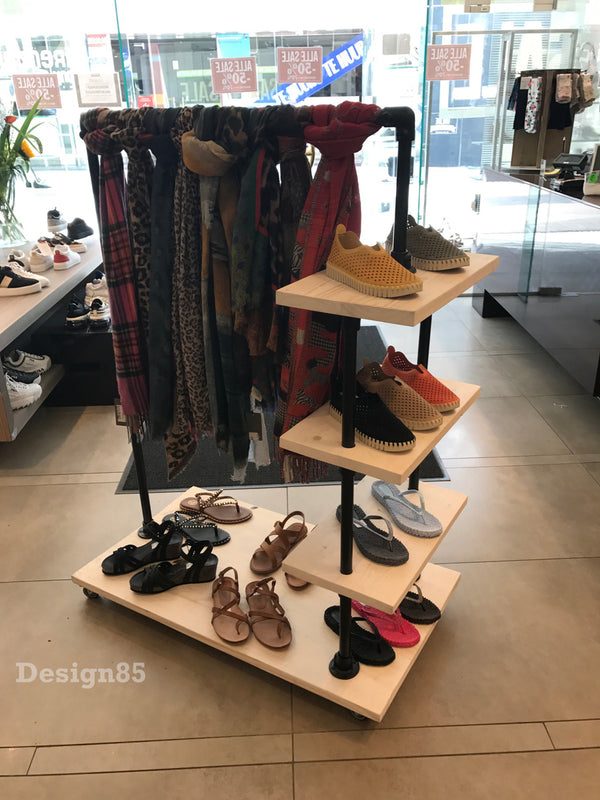 Steigerbuis kledingrek met zwarte steigerbuizen en diverse schappen waar schoenen op worden gepresenteerd en ruimte om sjaals aan op het hangen.