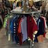 Rond steigerbuis kledingrek met kleding en sneakers in een moderne vintage kledingwinkel.