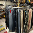 Steigerbuis kledingrek rond model met houten bovenblad en kleding rondom opgesteld in een winkelinterieur.