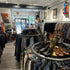 Rond industrieel kledingrek van steigerbuizen met shirts, sneakers en decoratie in een modewinkel.