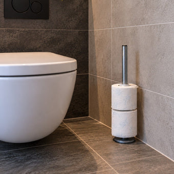 Steigerbuis toiletrolhouder Staand van industrieel staal met twee toiletrollen, stijlvol geplaatst naast een modern toilet.
