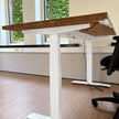Elektrisch verstelbaar zit sta bureau met een naturel vurenhouten blad, witte stalen poten en een ergonomisch ontwerp voor de werkplek.