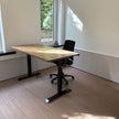 Industrieel zit sta bureau van hout met zwarte metalen poten en comfortabele bureaustoel bij het raam.