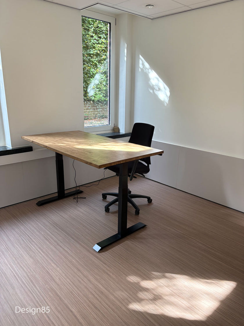 Industrieel zit sta bureau van hout met zwarte metalen poten en comfortabele bureaustoel bij het raam.